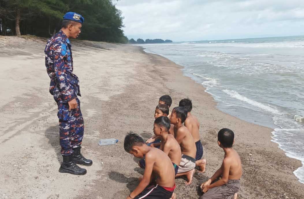 Personel polisi perairan Polres Padang Pariaman, Aipda Juwaldi menyambangi warga yang bermain di pantai. (tribratanews.sumbar.polri.go.id)