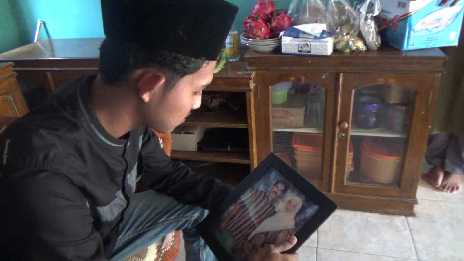 Naufal tatap foto kedua orang tuanya yang ia gantikan naik haji tahun ini. (eko)