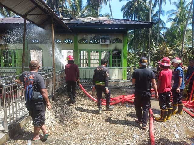 Petugas melakukan pendinginan di surau yang terbakar. (suhanews.co.id)