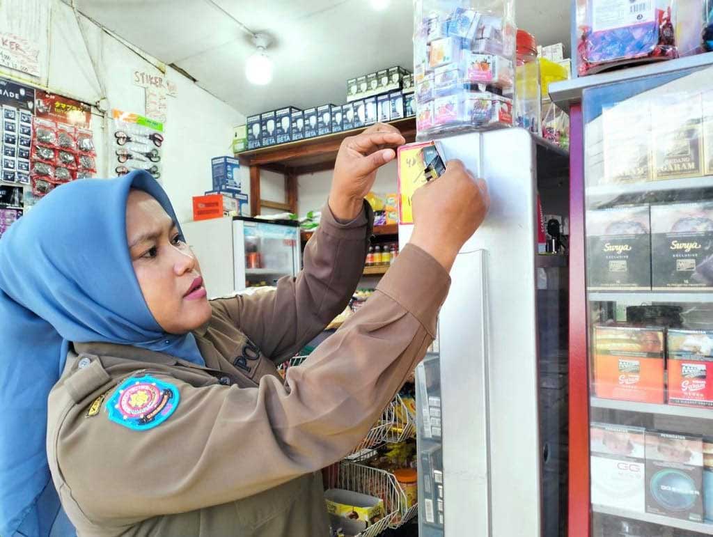 Petugas copot iklan rokok di warung. (kominfo)