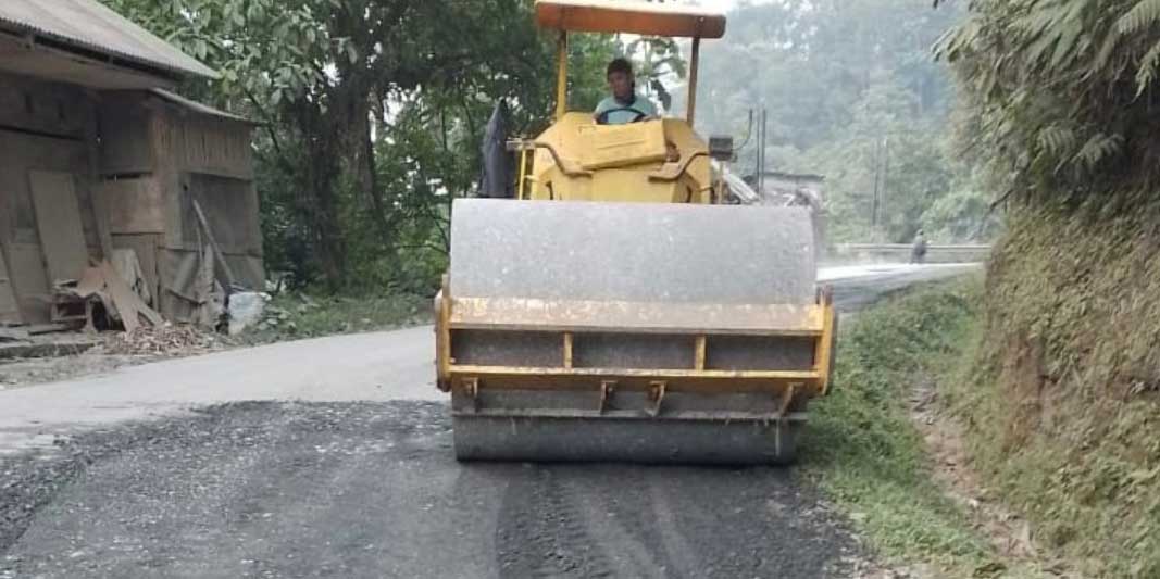 Alat berat tengah bekerja di jalan yang ditambal dengan aspal oleh pengusaha tambang
