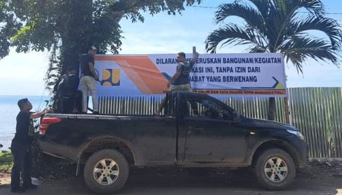 Petugas pasang larangan reklamasi di pantai.