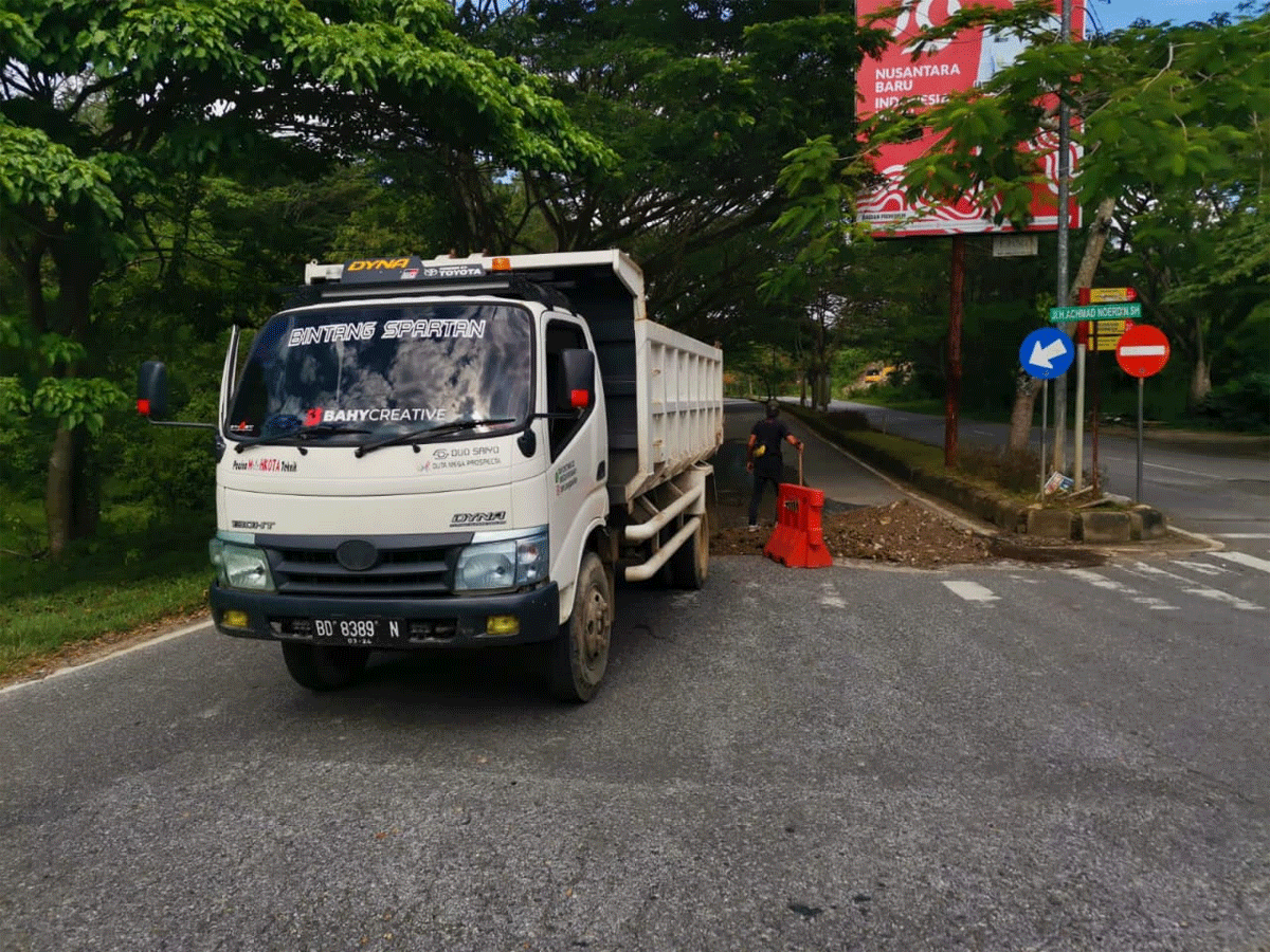 Alat berat dan material digunakan untuk menimbun jalan yang rusak di Sawahlunto
