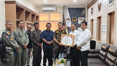 Ketua KPU Kuansing Wawan Ardi didampingi Sekretaris KPU Roni Sasnita serahkan penghargaan pada Kepala Satuan Polisi Pamong Praja Kuantan Singingi Rio Kesyterwandra, Jumat (7/2/2025) di Kantor Satpol PP Kuansing.