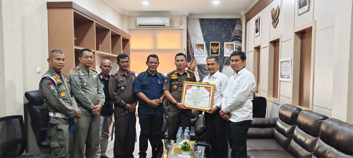 Ketua KPU Kuansing Wawan Ardi didampingi Sekretaris KPU Roni Sasnita serahkan penghargaan pada Kepala Satuan Polisi Pamong Praja Kuantan Singingi Rio Kesyterwandra, Jumat (7/2/2025) di Kantor Satpol PP Kuansing.