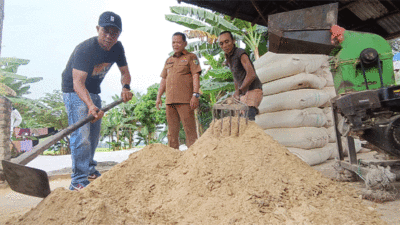 Zaini bersama Kades Naga Kisar Ahmad dan pekerjanya mengaduk pakan ternak yang sudah diolah menggunakan sisa ikan tilapia RSI, Selasa (29/7/2025)