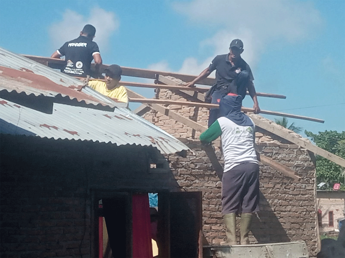 Pemasangan kembali atap rumah yang rusak setelah diterjang angin puting beliung.