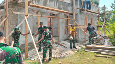 Personel TNI dan warga bahu membahu menyelesaikan rumah Parnen.