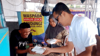 Salah seorang pedagang kaki lima gembira menerima nasi kotak program Jumat Berkah yang digagas duo legislator NasDem di Jember, Jawa Timur, Jumat (17//2026). (Foto: Mahrus Sholih)