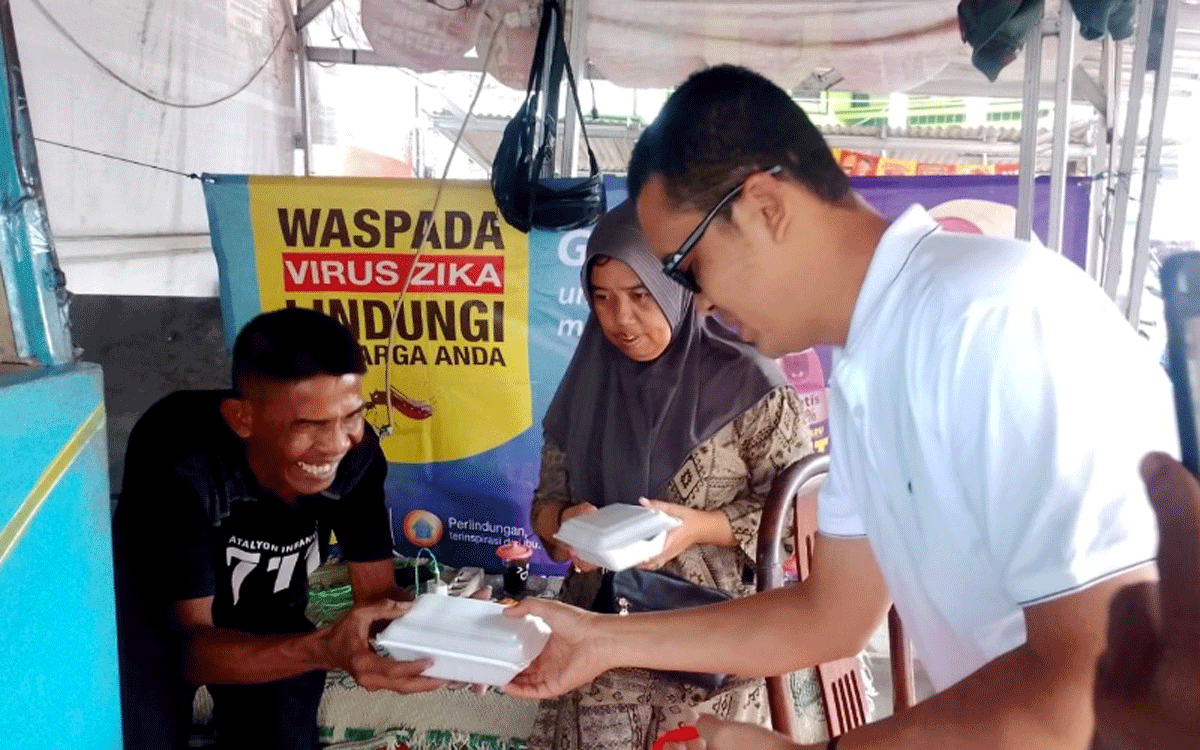 Salah seorang pedagang kaki lima gembira menerima nasi kotak program Jumat Berkah yang digagas duo legislator NasDem di Jember, Jawa Timur, Jumat (17//2026). (Foto: Mahrus Sholih)